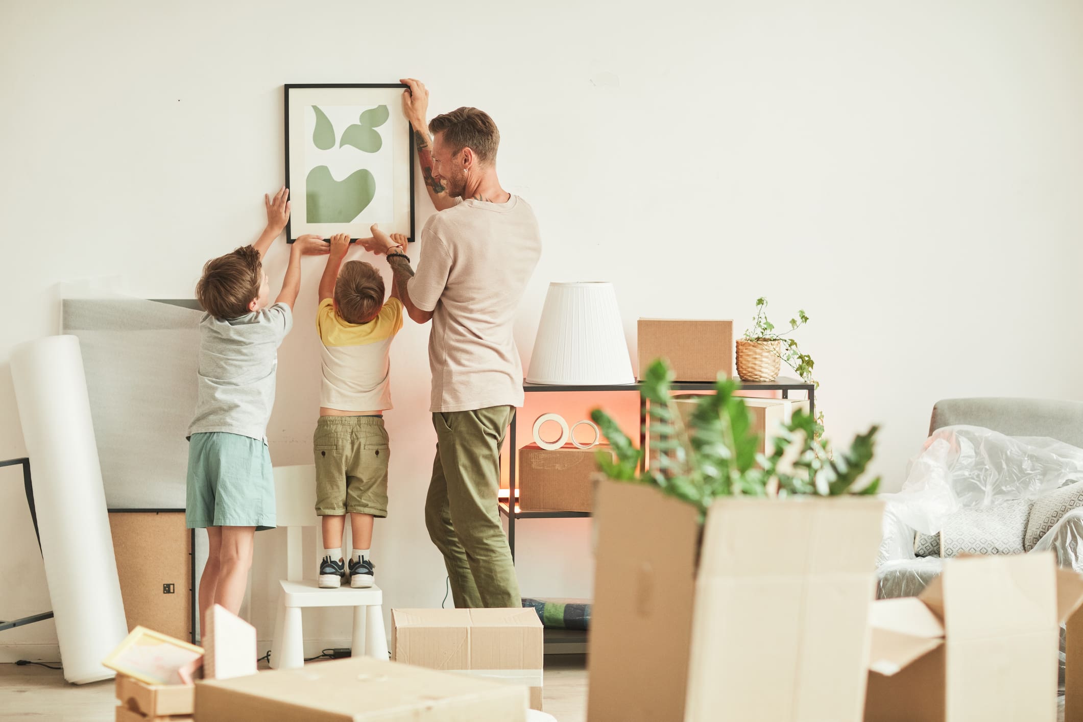 Apa gyermekeivel egy képet tesznek fel a falra az új lakásban.