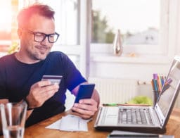 férfi laptoppal, fizikai bankkártyát digitalizál mobilfizetéshez