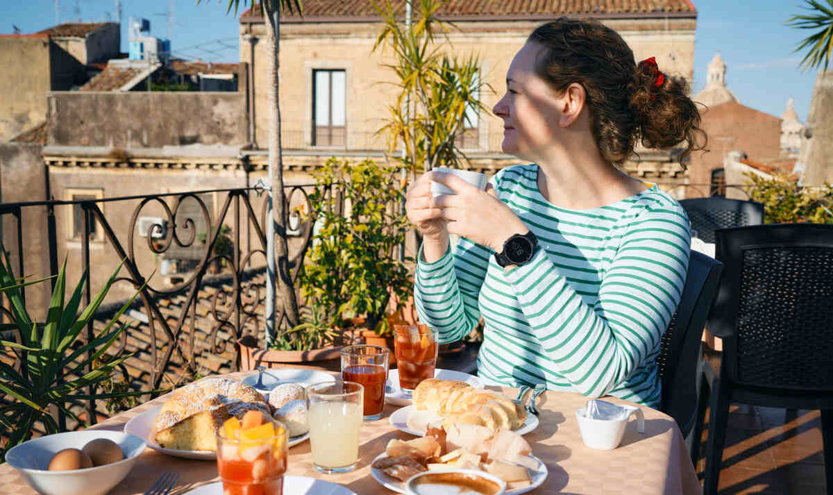 nő asztalnál ül és reggelizik Szicíliában, külföldi nyaraláson, euró váltása után