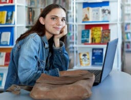 egyetemi hallgató a könyvtárban, laptop előtt, Diákhitel Számla igénylése közben