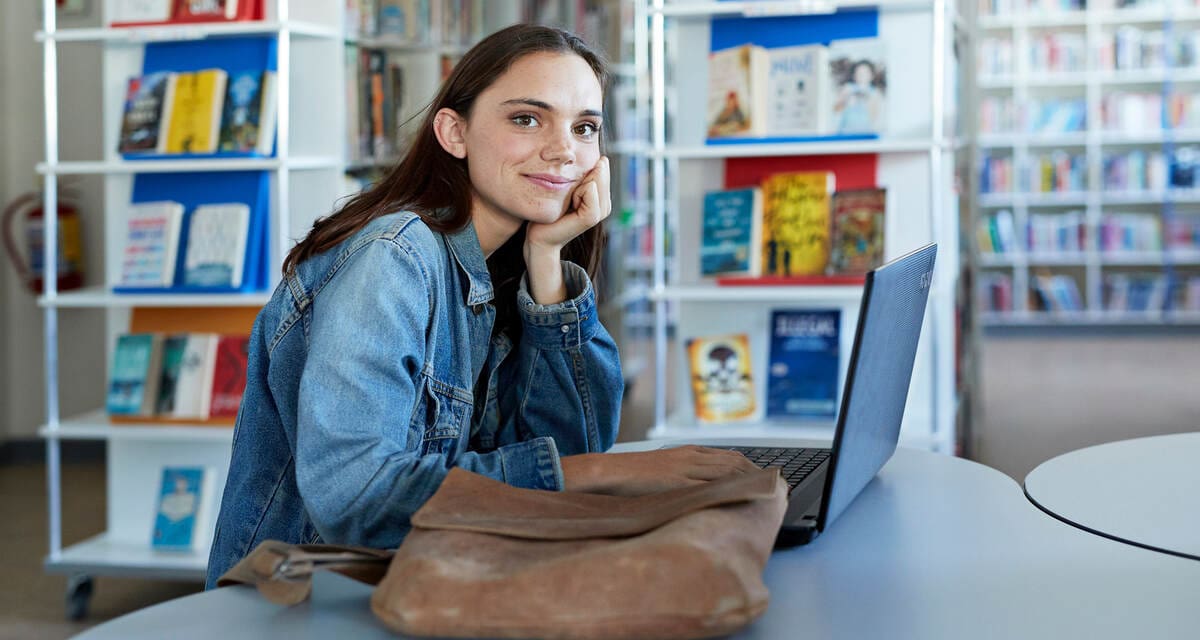 egyetemi hallgató a könyvtárban, laptop előtt, Diákhitel Számla igénylése közben