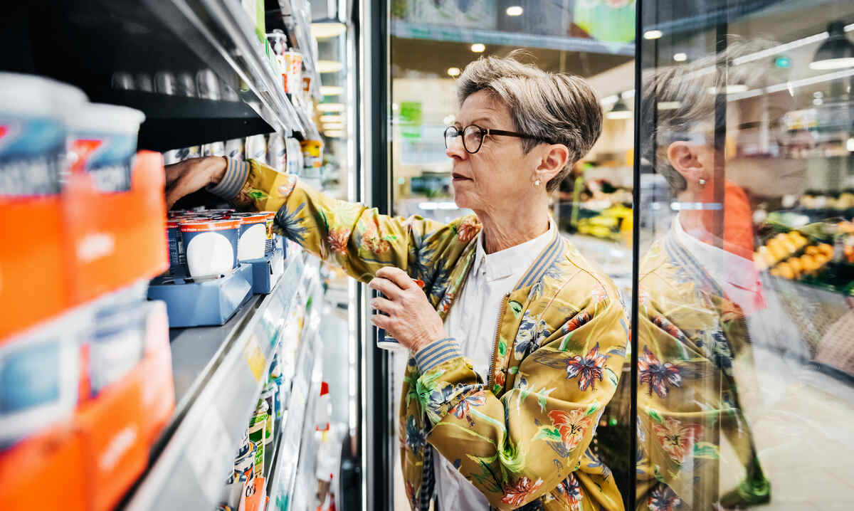élelmiszer-infláció a boltban: idősebb hölgy a tejtermékek között válogat