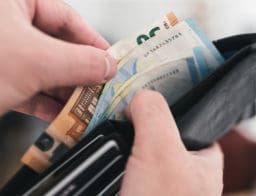 Egy férfikéz nyitja a pénztárcát, benne euró bankjegyek.