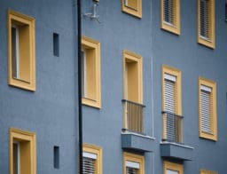 lakóparki bérház ablakai, erkélyei, kék és sárga, mnb kamatdöntés