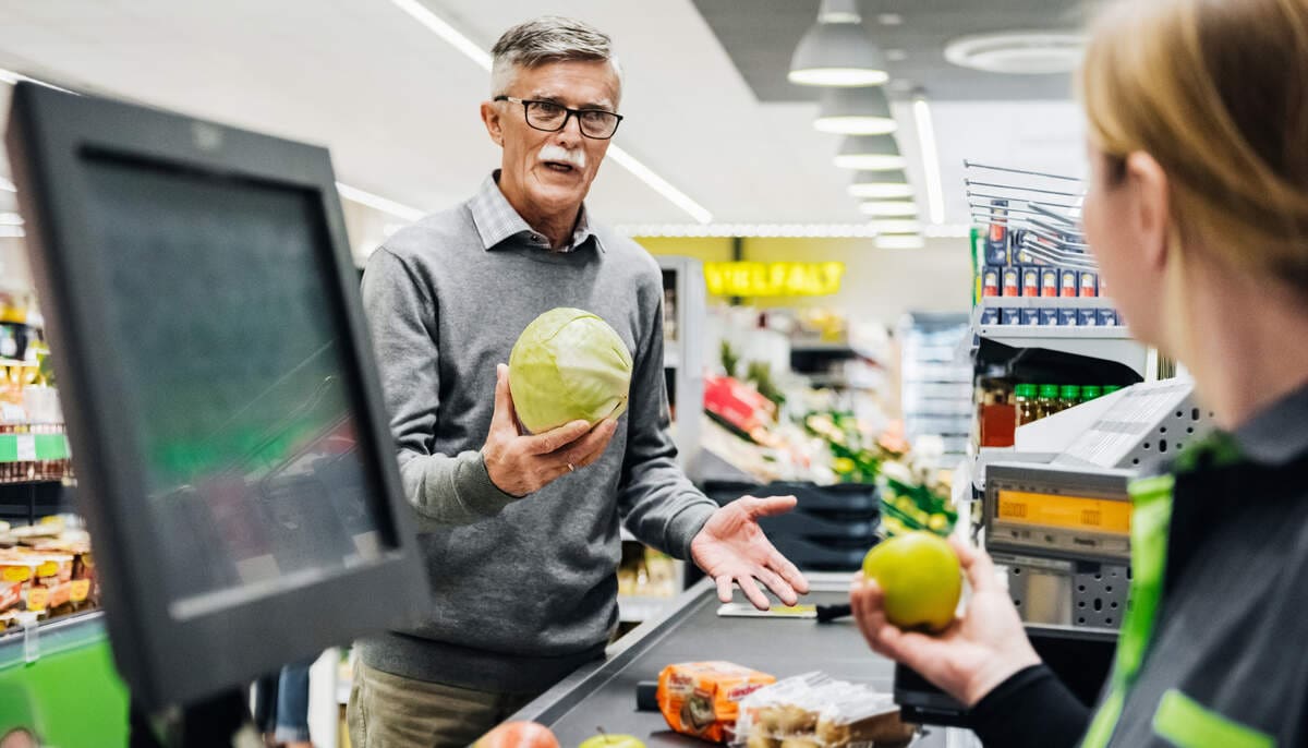 nyugdíjas vásárló boltban kezében saláta készpénzt vesz fel cashback segítségével pénztárostól