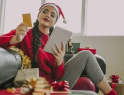 nő karácsonyra készül, ajándékok társaságában, kezében hitelkártya, készpénzfelvétel és vásárlás