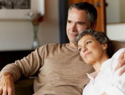 középkorú pár a kanapén ülve, nappaliban azon tanakodik, mekkora havi nyugdíj-megtakarítás szükséges