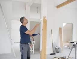 Egy szobafestő férfi munka közben egy szobában.
